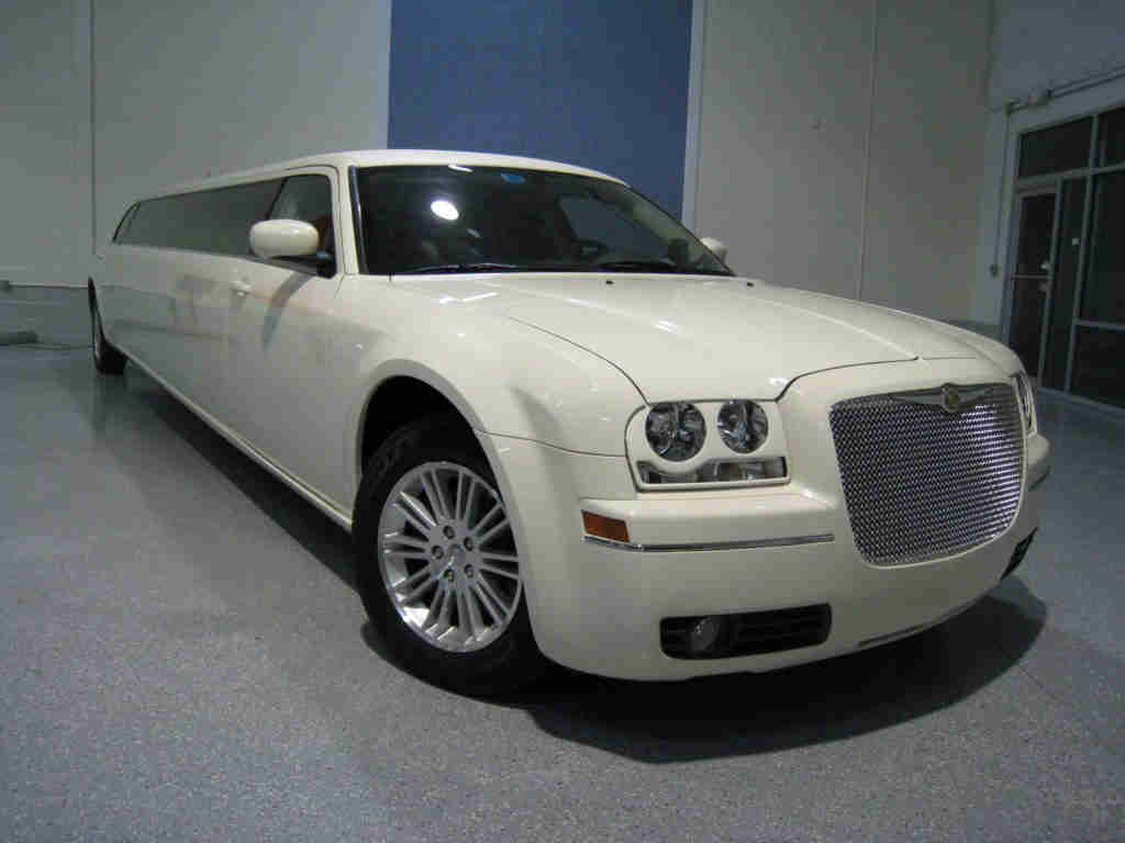 A white limo is parked in the garage.