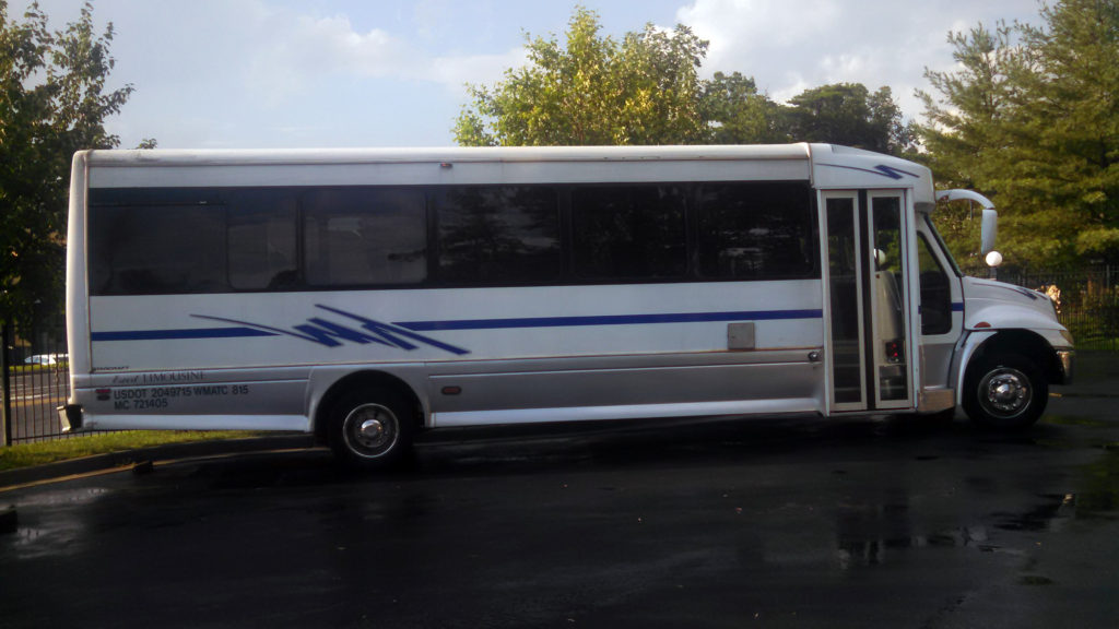 A white bus with blue stripes parked in the parking lot.