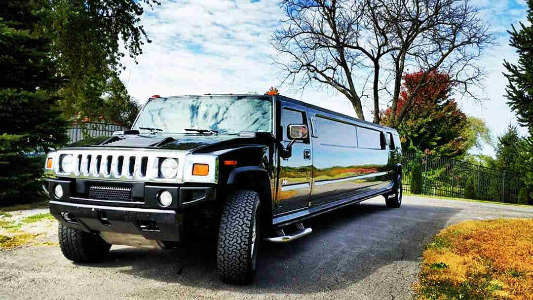 A black hummer limo parked on the side of a road.
