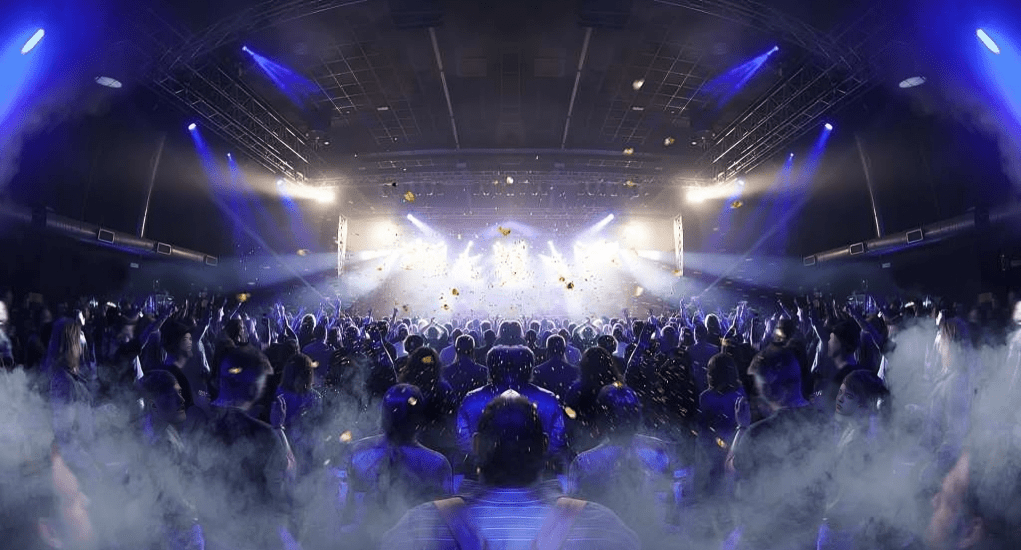 Concert crowd under blue stage lights.