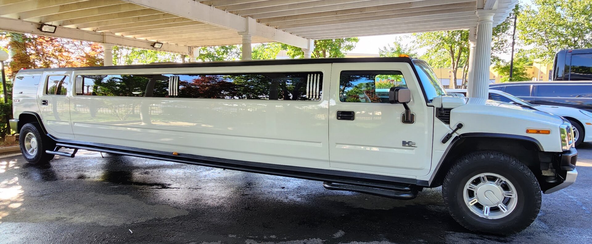 White stretch Hummer limousine under a canopy.