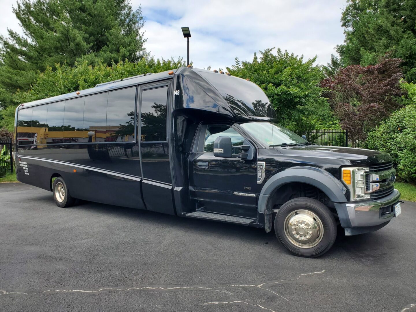 Black shuttle bus parked on asphalt driveway.